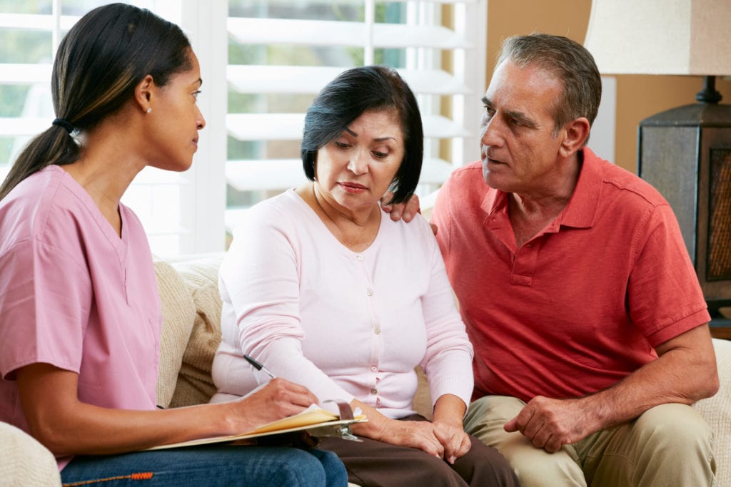 Nurse Making Notes During Home Visit With Senior Couple