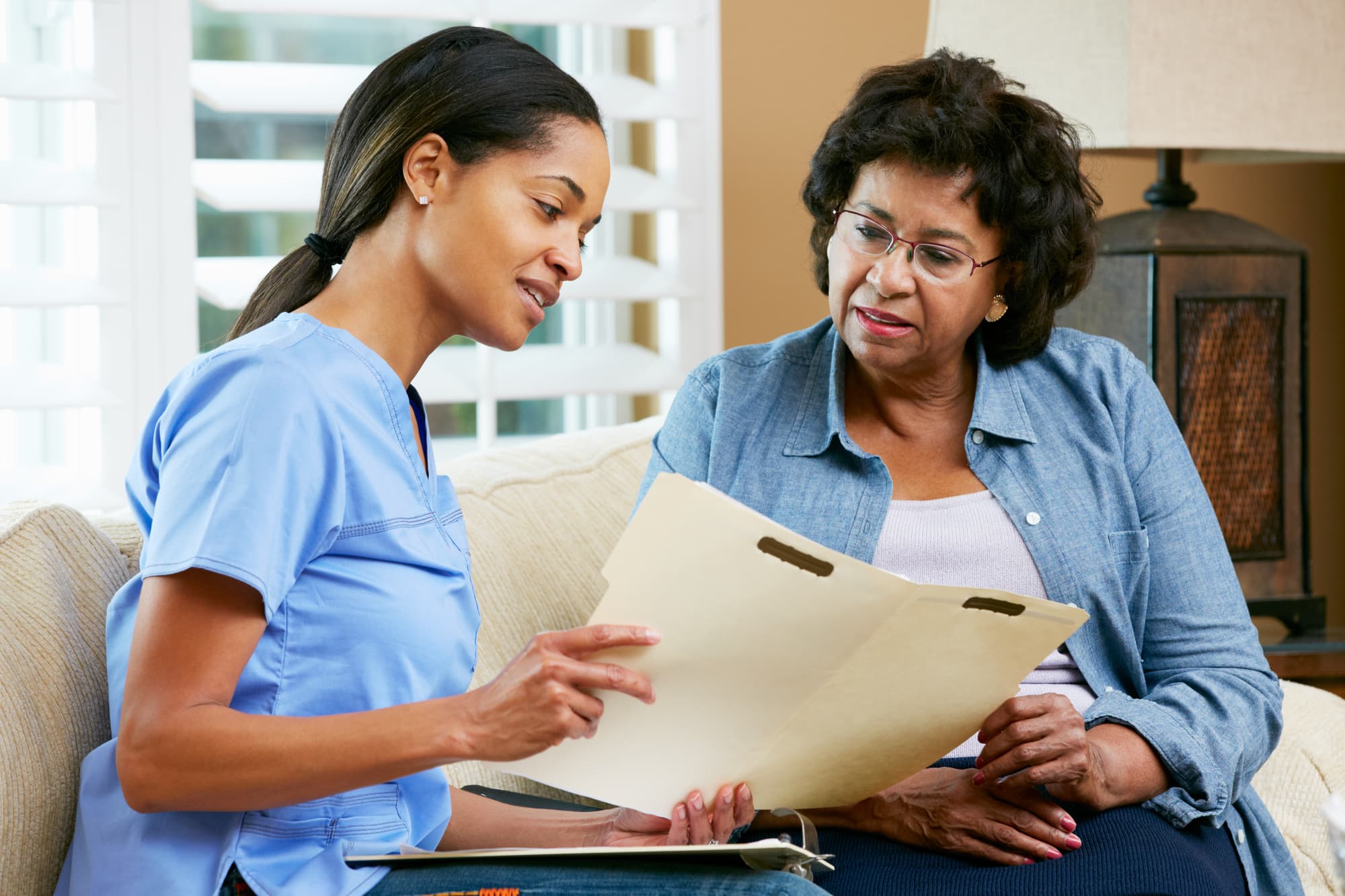 Home care provider Discussing Records With Senior Female Patient During Home Visit